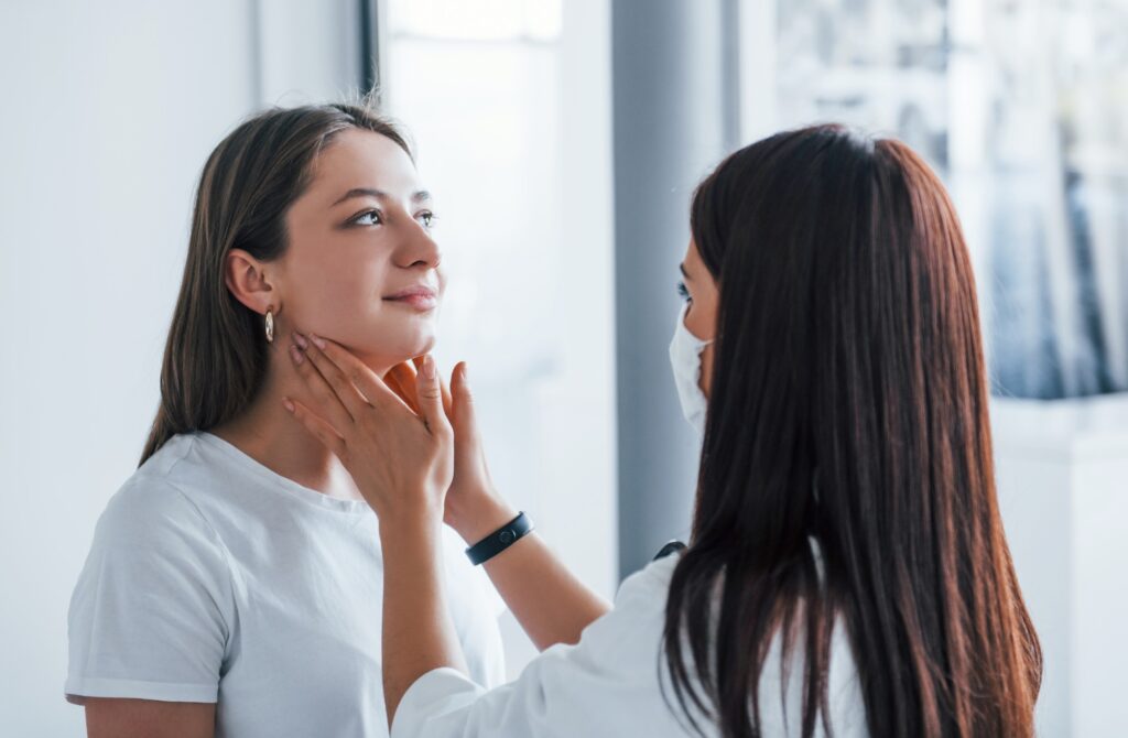 Checking lymph nodes and throat. Young woman have a visit with female doctor in modern clinic