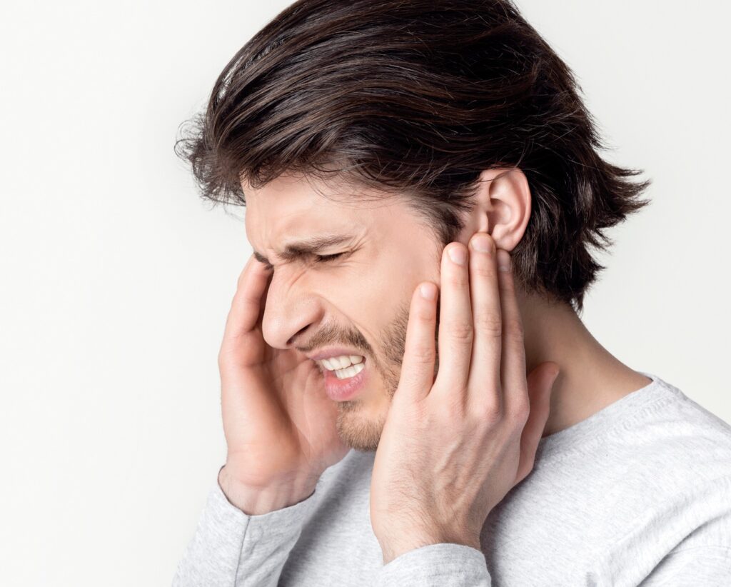 Man with earache is holding sore spot