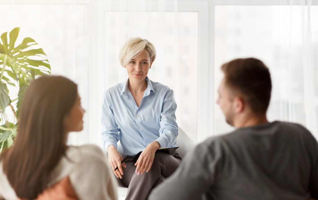 Psychologist Smiling Looking At Couple's Reconciliation Sitting In Office