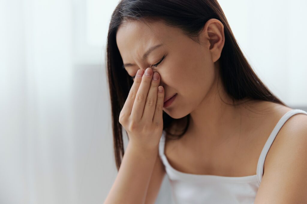 Rhinitis Sinusitis Flu. Suffering tormented tanned beautiful young Asian woman hold hand on nose