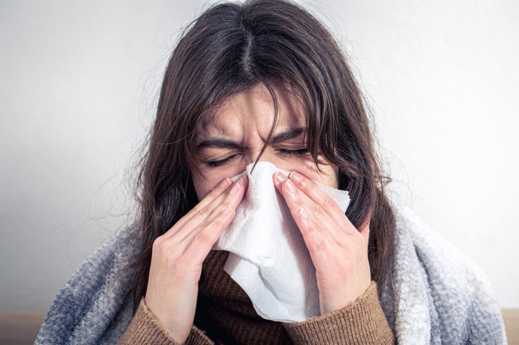 A sick young woman at home on the sofa with a cold.