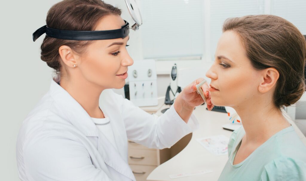 Diagnosis and treatment of nasal disease. ENT doctor examines nose of female patient